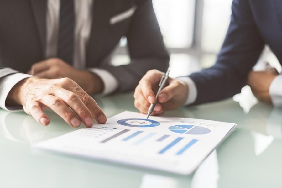 To personer diskuterer diagrammer og data i en profesjonell setting, som illustrerer telemarketingtjenester for Byggfakta rettet mot byggebransjen