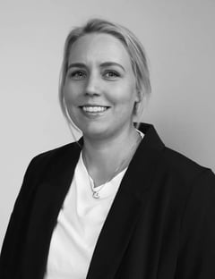 Kristine Andersen, Customer Success Manager, smilende og avbildet i svart-hvitt, iført en mørk jakke over en lys topp