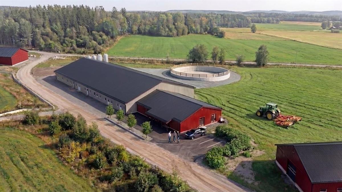 llustrasjon av grisefjøset på Hvam videregående skole ved ferdigstillelse, med rødt fjøsbygg med sort tak, rundkjøringsgjerde, traktor og jorder i bakgrunnen. Foto: Nordplan AS